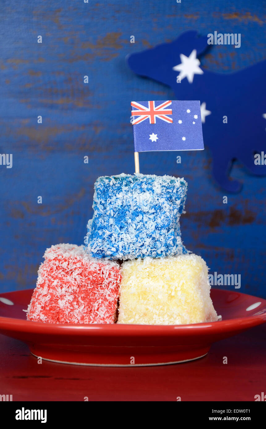 Heureux l'Australie jour rouge, blanc et bleu lamingtons sur rouge et bleu en bois recyclé sombre arrière-plan. Gros plan vertical. Banque D'Images