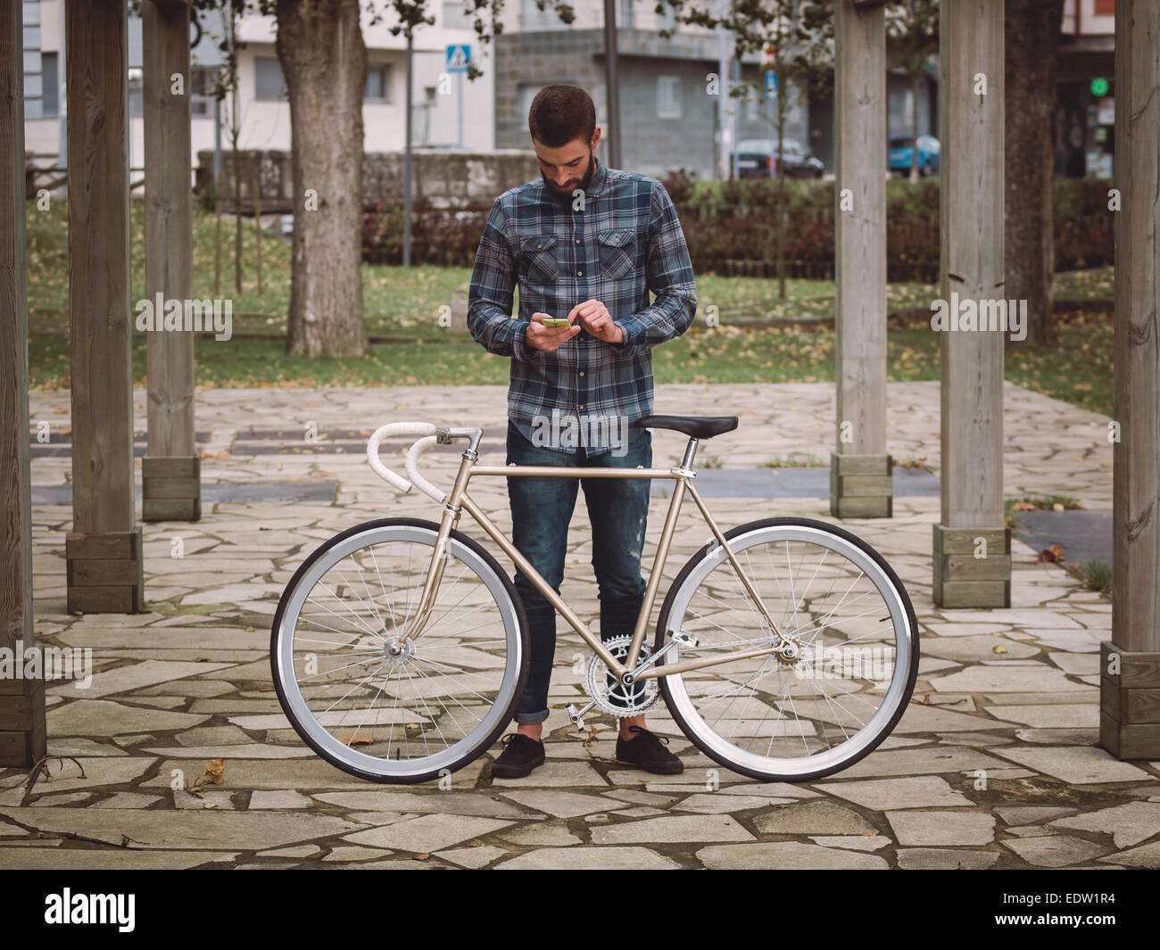 Hipster homme avec un fixie bike et smartphone dans un parc en plein air Banque D'Images