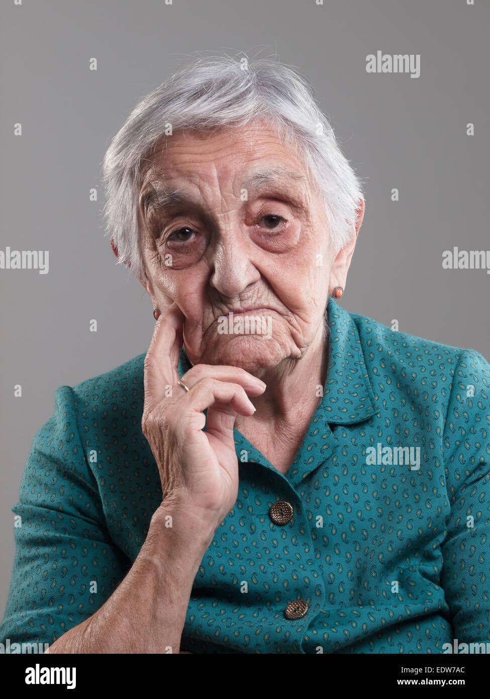 Femme âgée portrait dans un studio photo. Vieille Femme avait sa main sur le menton et triste Banque D'Images