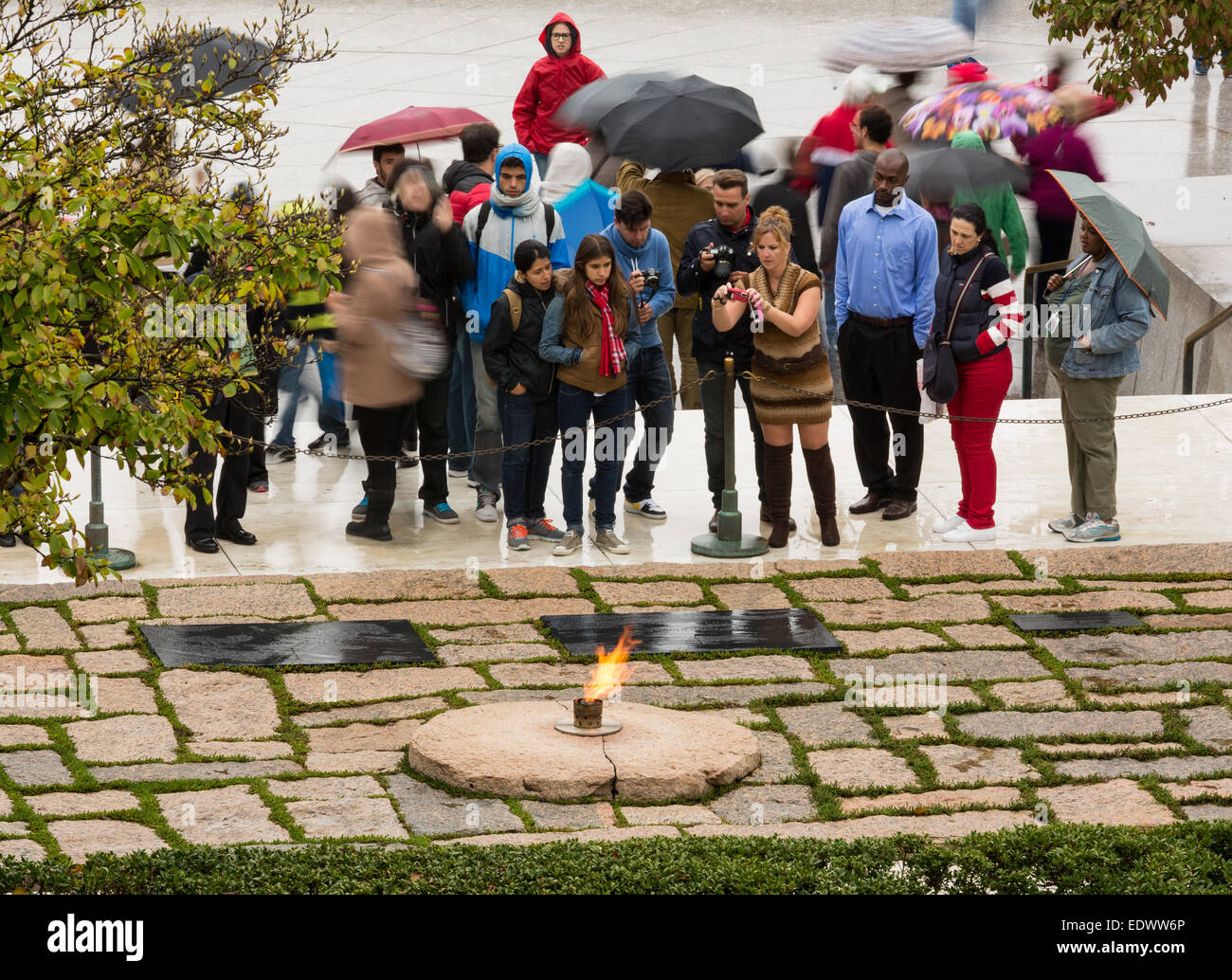 Les touristes dans la pluie à prendre des photos à la flamme éternelle mémoire du Président John F Kennedy au cimetière d'Arlington près de Washingt Banque D'Images