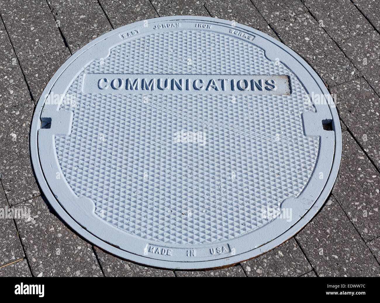 Détail de communications peint en gris couvercle dans la chaussée ou trottoir pavé de briques Banque D'Images