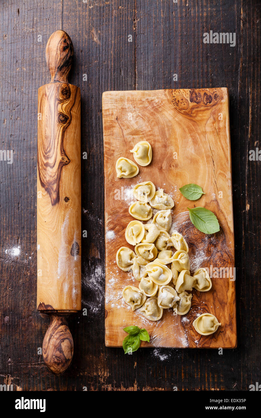 Des feuilles de basilic tortellini et matières premières sur fond de bois foncé Banque D'Images