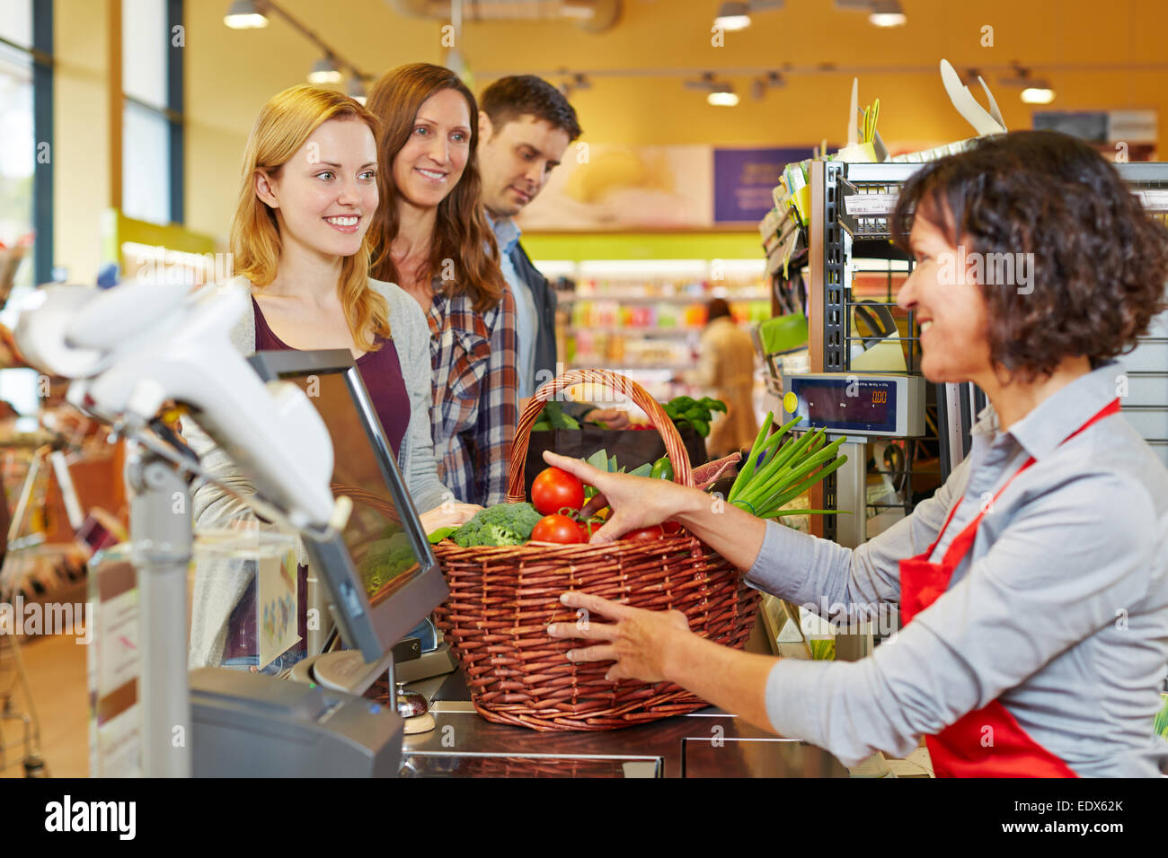 Jeune femme de payer panier de provisions at supermarket checkout Banque D'Images