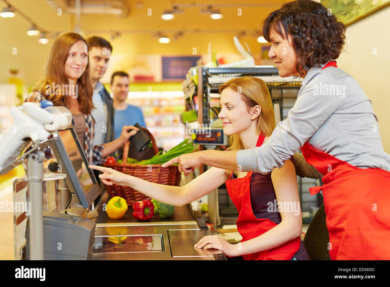 Personnes âgées aide vendeuse jeune femme at supermarket checkout Banque D'Images