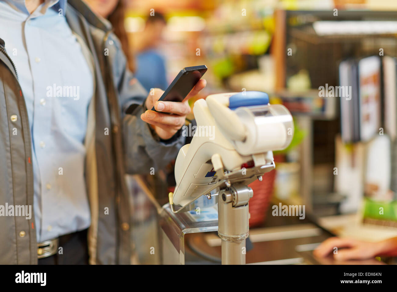 L'homme de payer avec son smartphone sans fil at supermarket checkout Banque D'Images