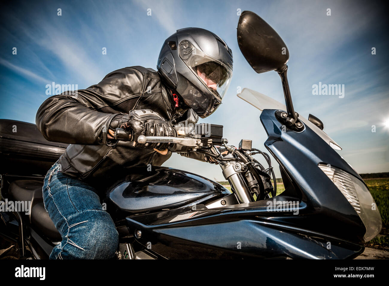 Biker dans casque et blouson de cuir racing sur la route Banque D'Images