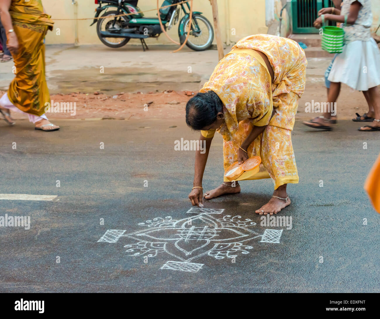 THANJAVOUR, INDE - Le 14 février : une femme non identifiée des ornements de peintures de farine de riz sur la route asphaltée. L'Inde, le Tamil Nadu, Thanj Banque D'Images