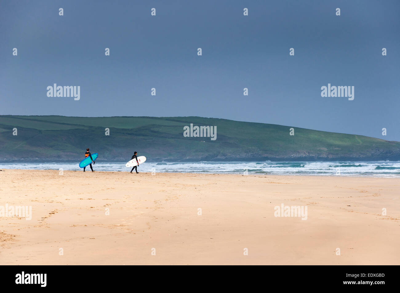Surfers faire leur chemin vers la mer, transportant leurs conseils sur la plage de Crantock près de Newquay, Cornwall. Banque D'Images