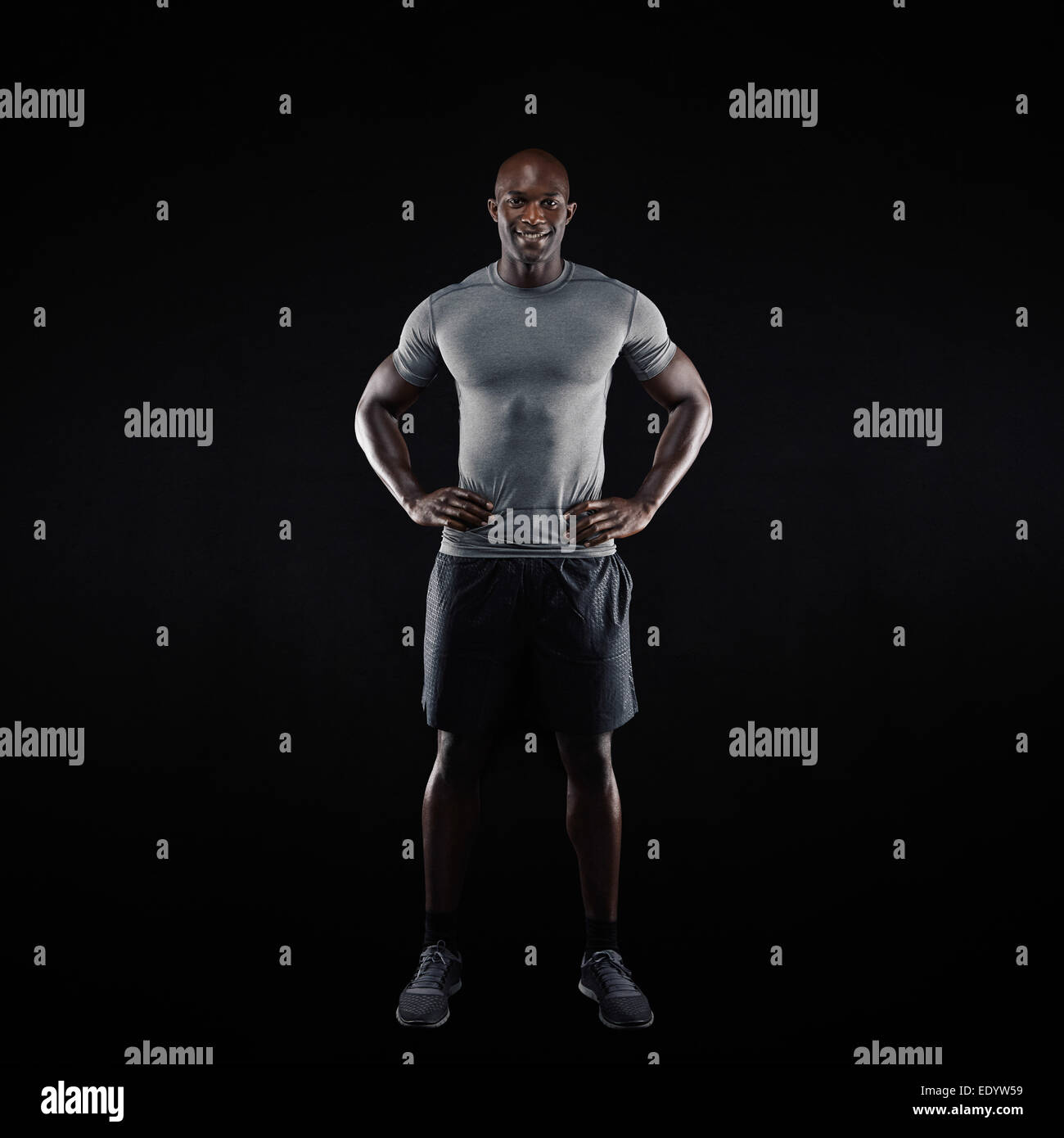 Longueur totale image of young man standing sur fond noir. En athlète africain musculaire sportswear. Banque D'Images