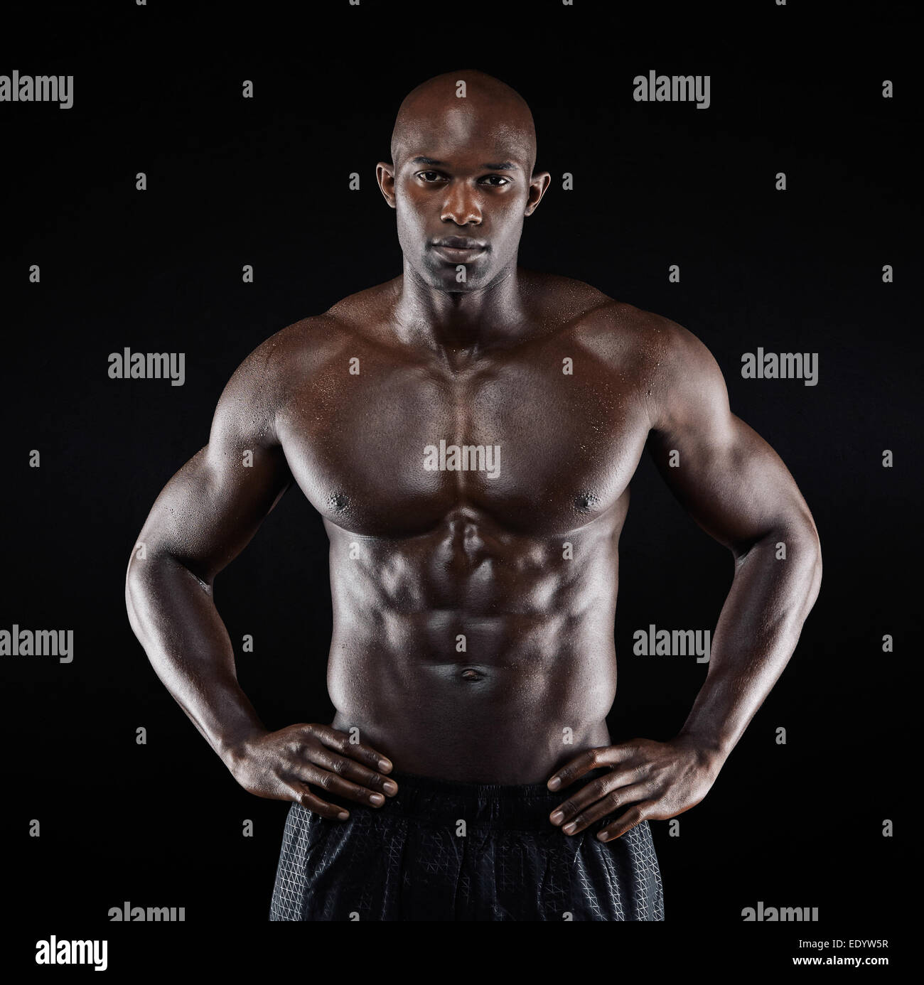 Portrait of a strong afro-american man showing off son physique contre l'arrière-plan noir. Shirtless male model posing. Banque D'Images