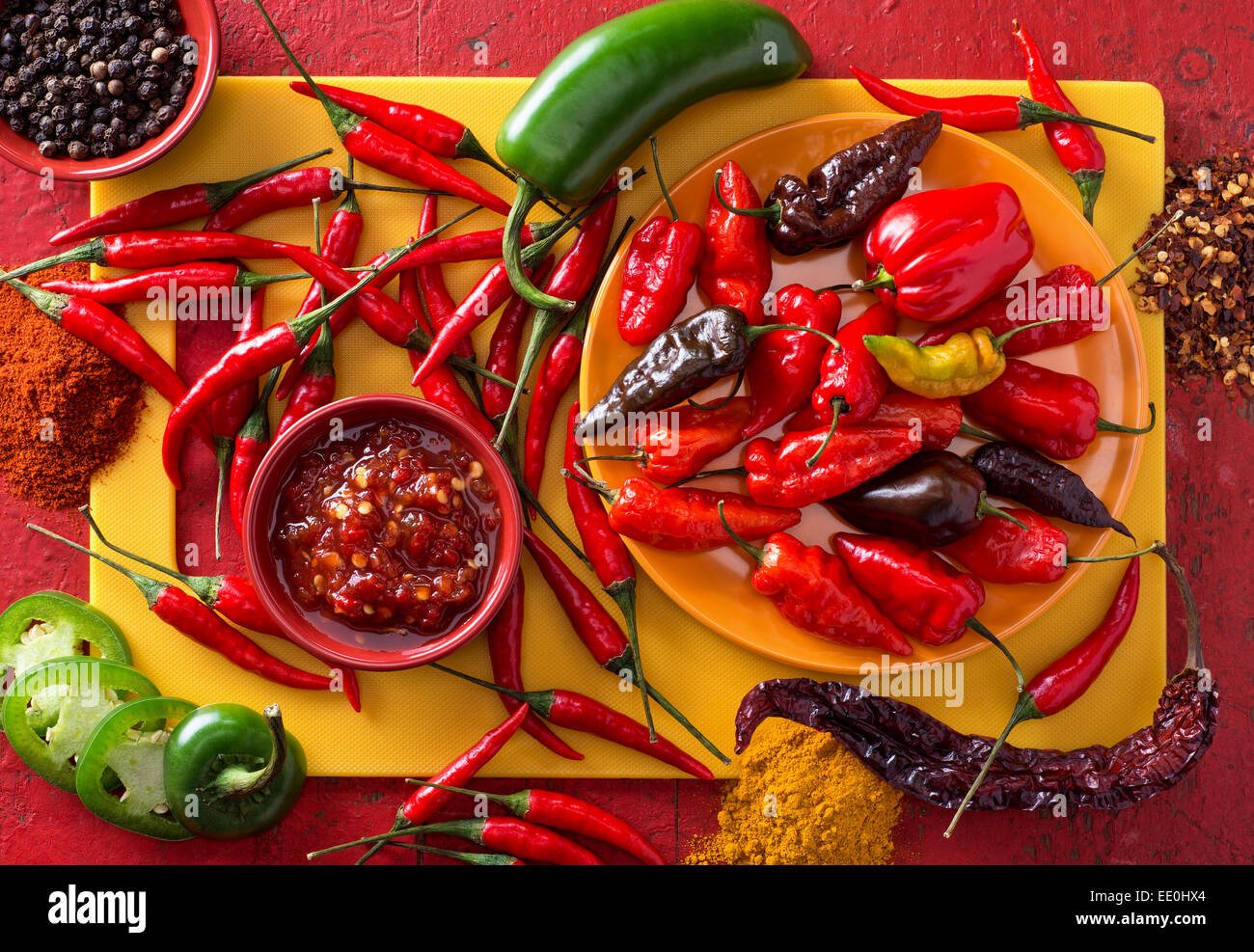 Un groupe de piments de couleurs vives sur un fond rouge. Banque D'Images