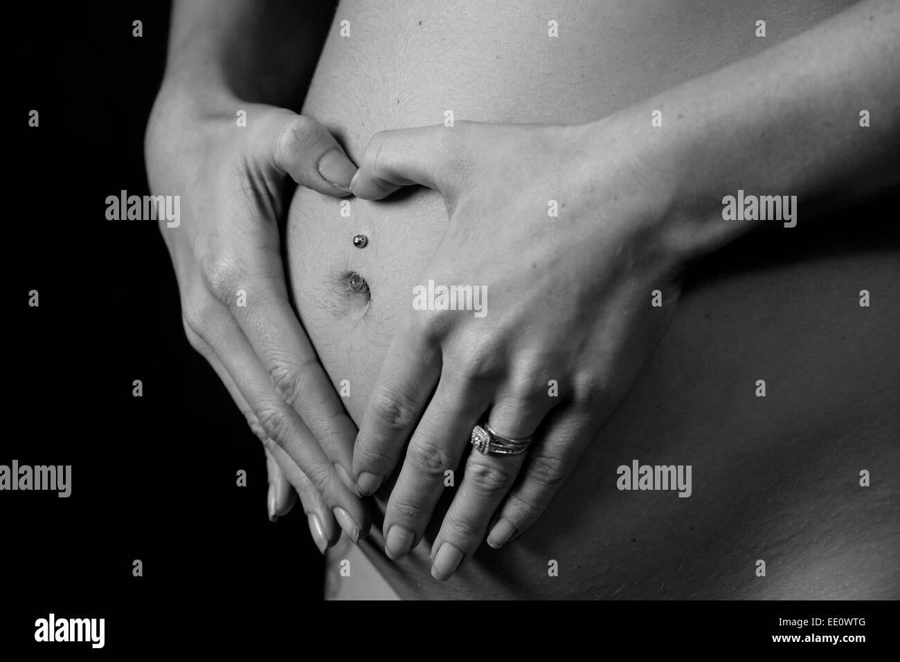 Une femme tient ses mains sur son ventre alors que la création d'enceintes ou de percuter une forme de coeur symbolisant l'amour. Banque D'Images