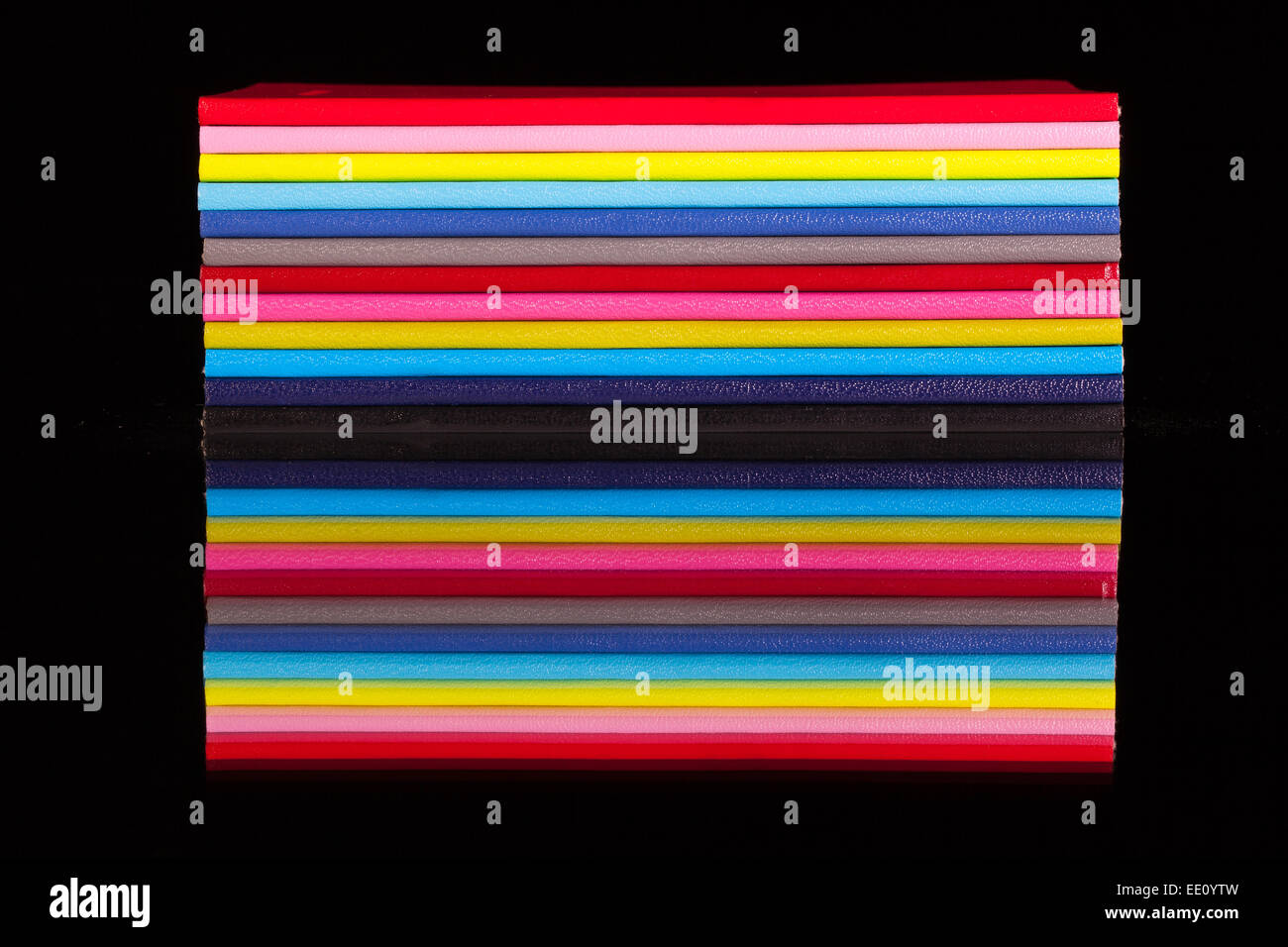 Douze journaux de couleur différente sur un bureau en verre noir Banque D'Images