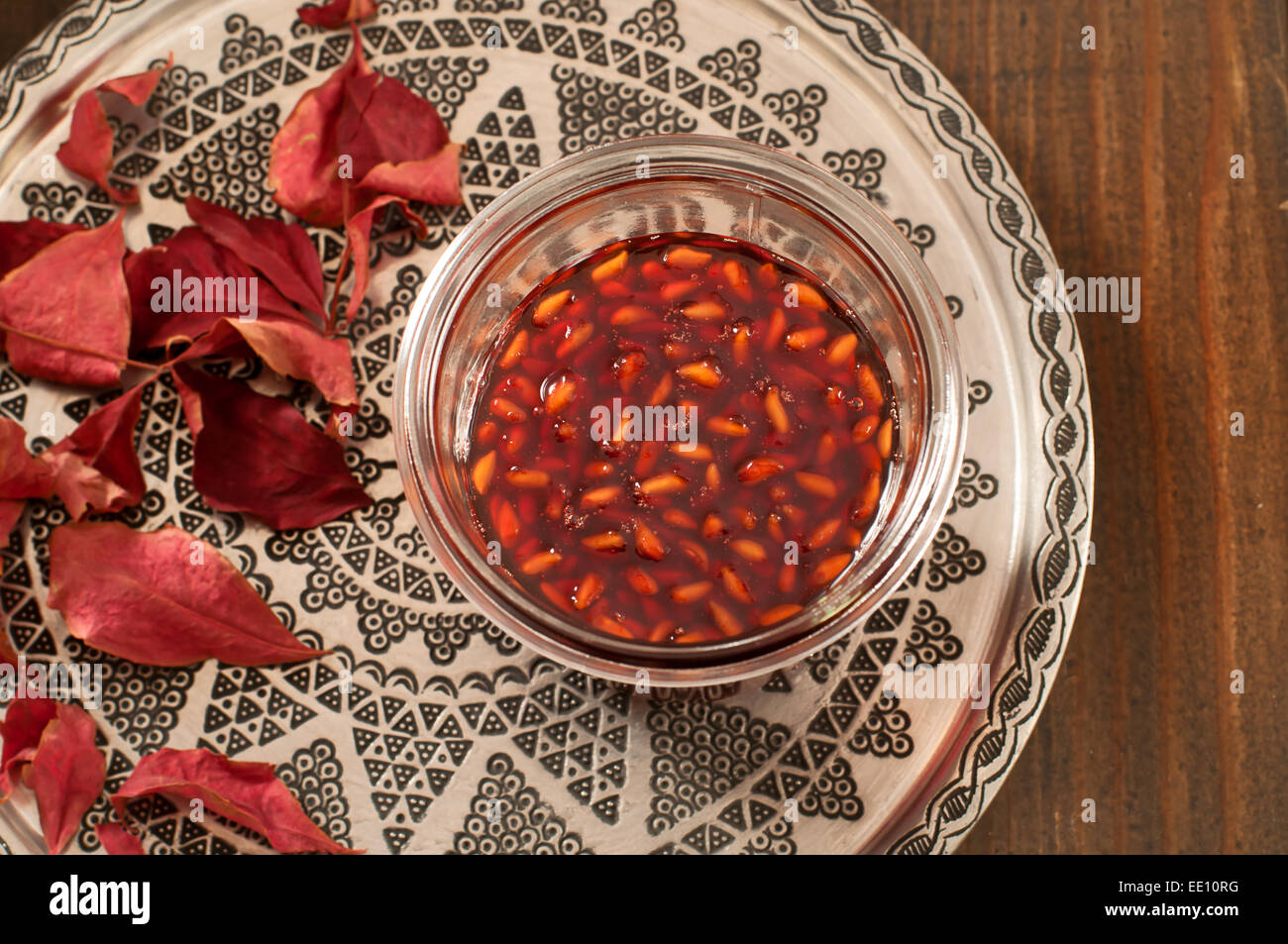 Grenade maison de la confiture dans un bocal en verre sur une plaque de cuivre à côté de feuilles d'automne Banque D'Images