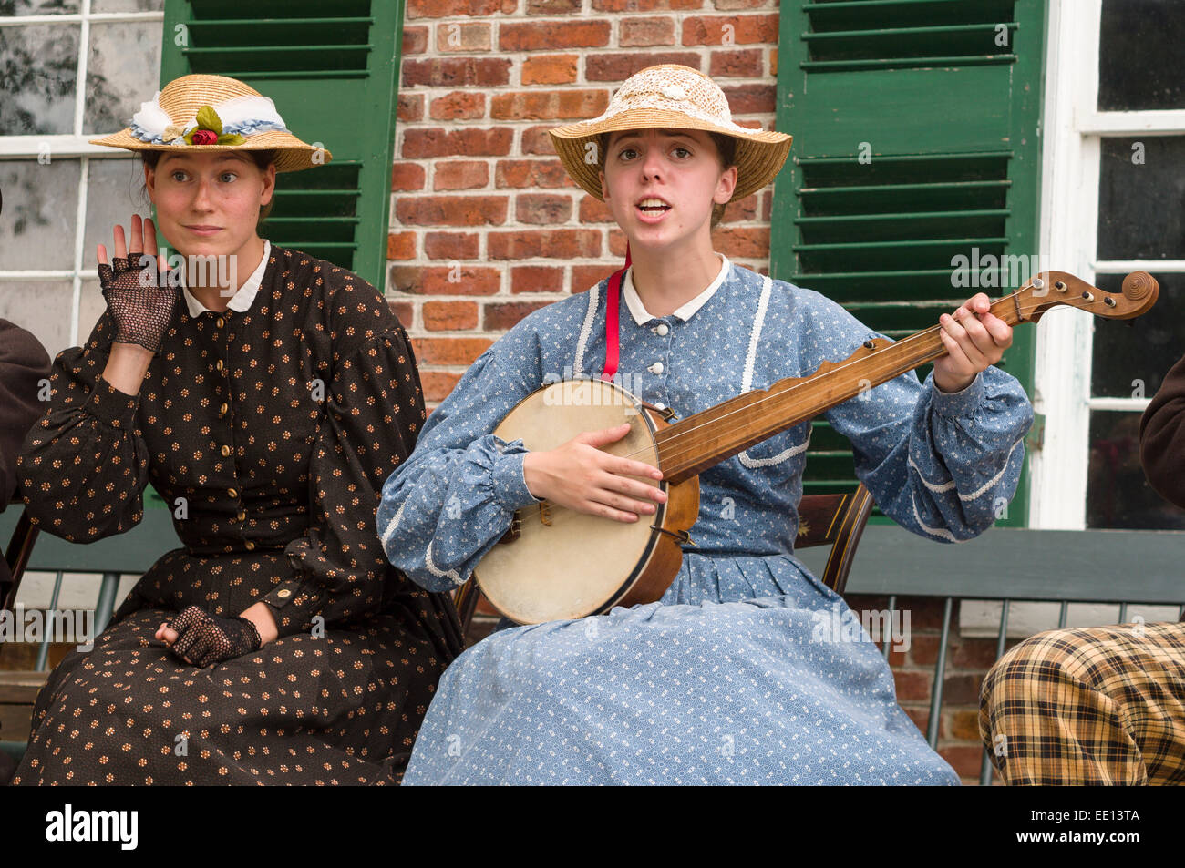 Animations musicales au Upper Canada Village. Une femme est à l'écoute de la réaction de l'auditoire tandis que l'autre chante et joue un banjo. Banque D'Images