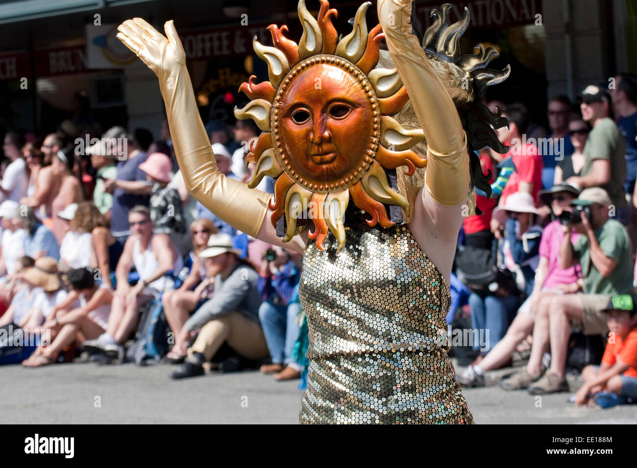 Une femme en robe d'or et du soleil sur un masque au cours de la rue Fremont Solstice Parade à Seattle, WA Banque D'Images
