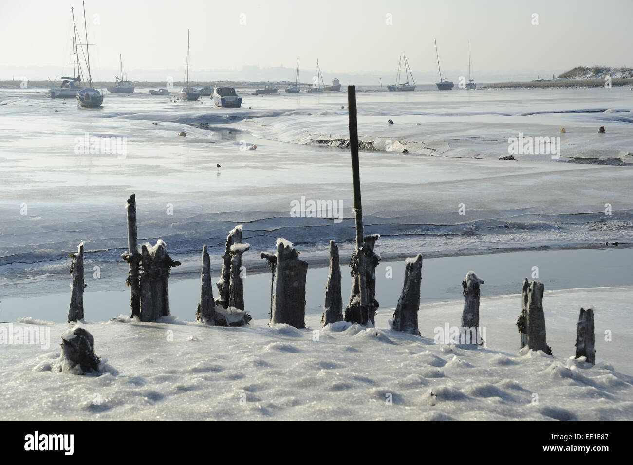 Vue sur les vasières et marais salant couvert de glace, avec l'ancien débarcadère et bateaux à voile à distance, Holbrook Creek, rivière Stour, estuaire de la Stour, Holbrook, Shotley Péninsule, Suffolk, Angleterre, Février Banque D'Images