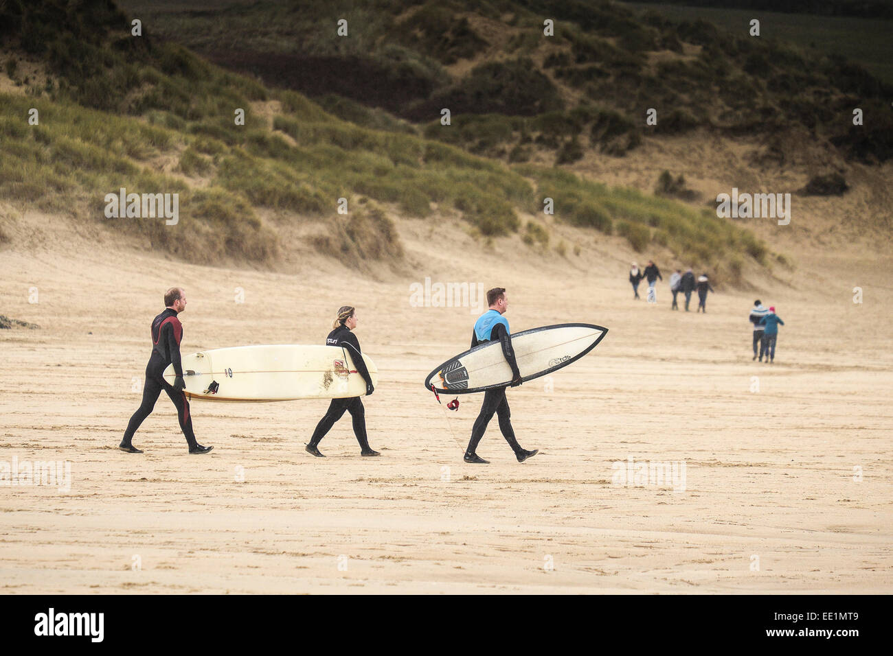 Surfers portent leurs planches le long de plage de Crantock à Newquay Banque D'Images