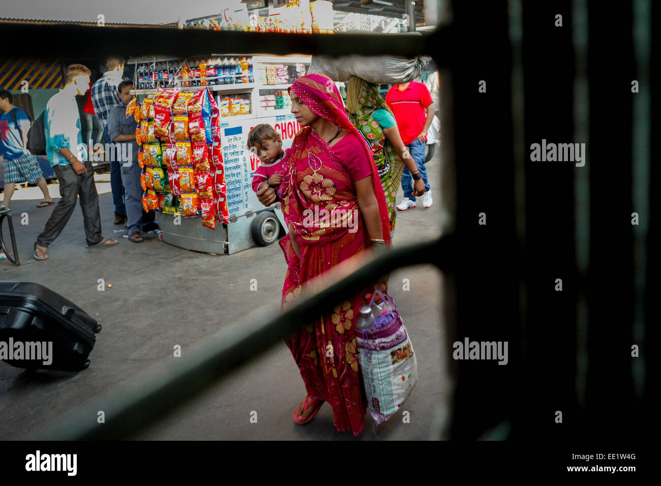Une femme tenant un bébé alors qu'elle marche sur la plate-forme passager à la gare de New Delhi, en Inde. Banque D'Images