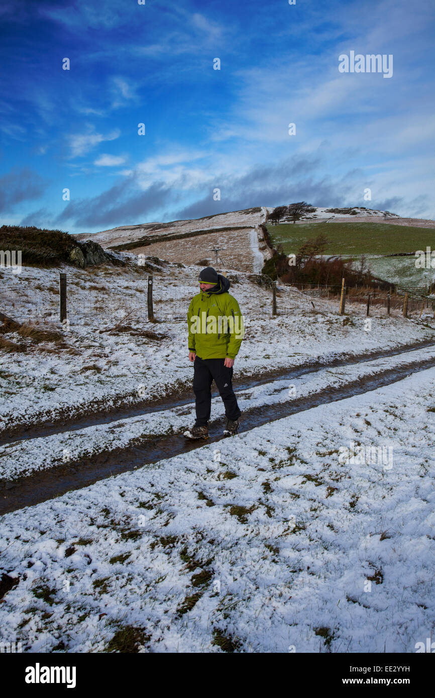 Une personne qui marche le long d'un chemin d'Offas Dyke couvertes de neige près de Moel y Parc dans la gamme Clwydian ou Clwydian Hills sur le côté de la gamme Denbighshire, Wales, UK Banque D'Images