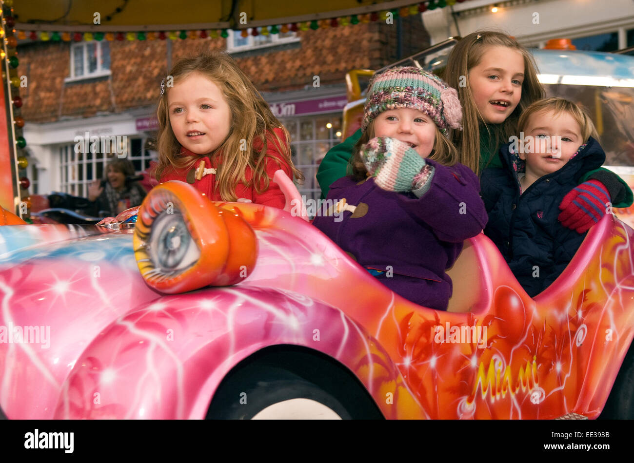 Groupe de 4 enfants s'amusant sur un champ de foire ride at an outdoor marché de noël, high street, Haslemere, Surrey, UK 20 décembre. Banque D'Images