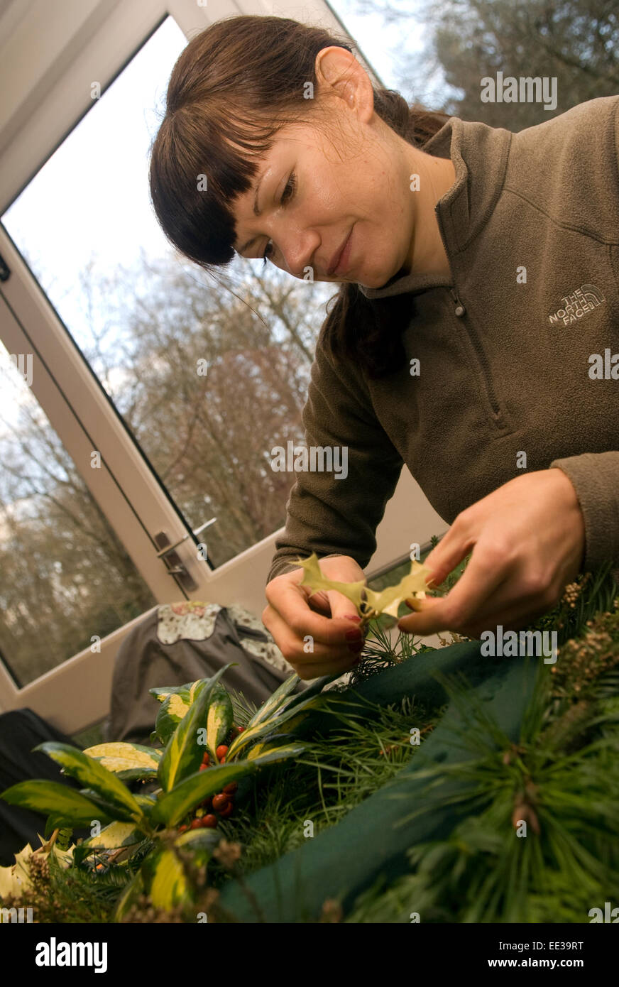 Femme prenant part à un atelier de fabrication de couronnes de Noël, Witley, UK. Banque D'Images