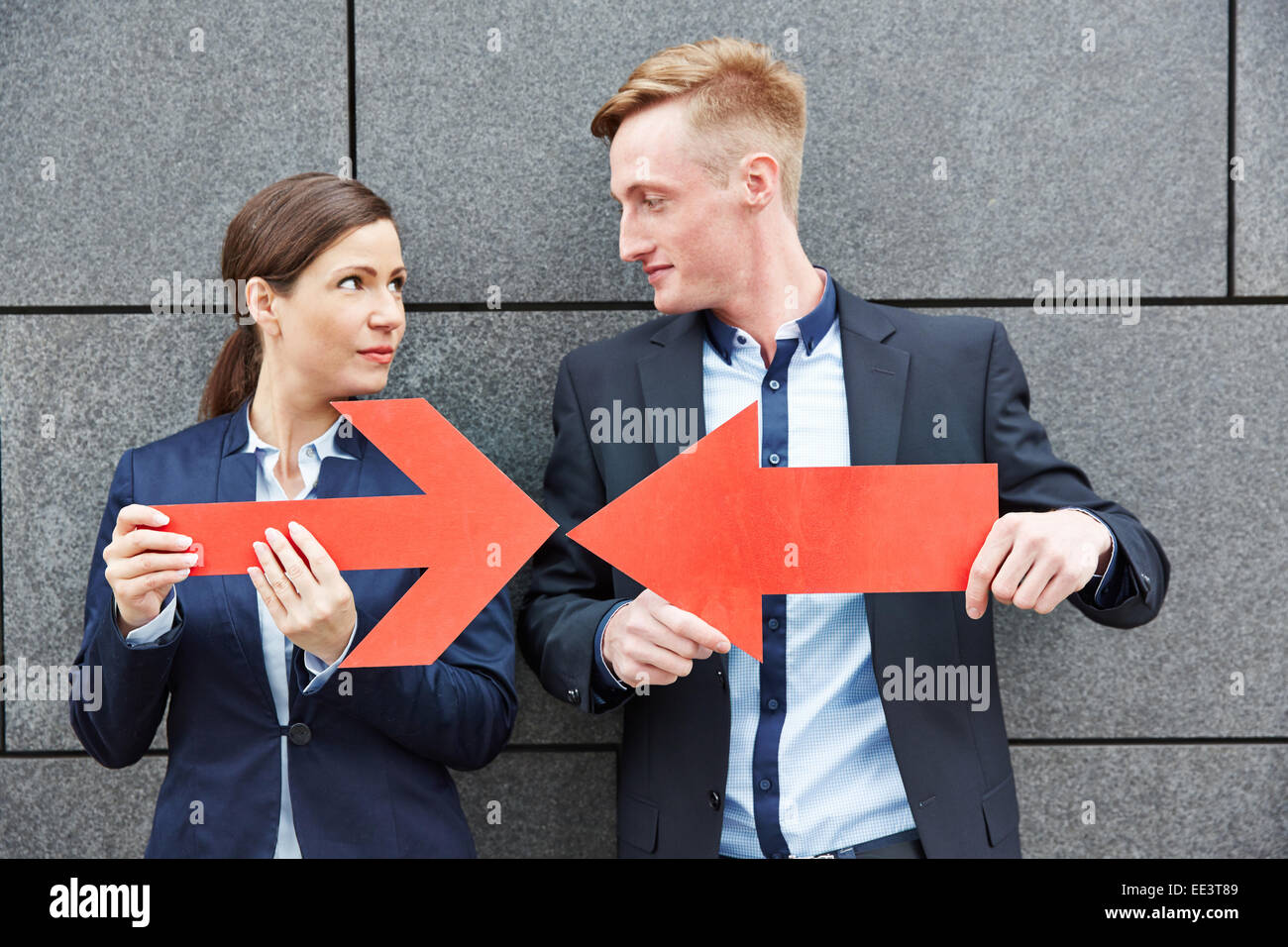 Business man and woman holding deux grosses flèches rouges les uns contre les autres Banque D'Images