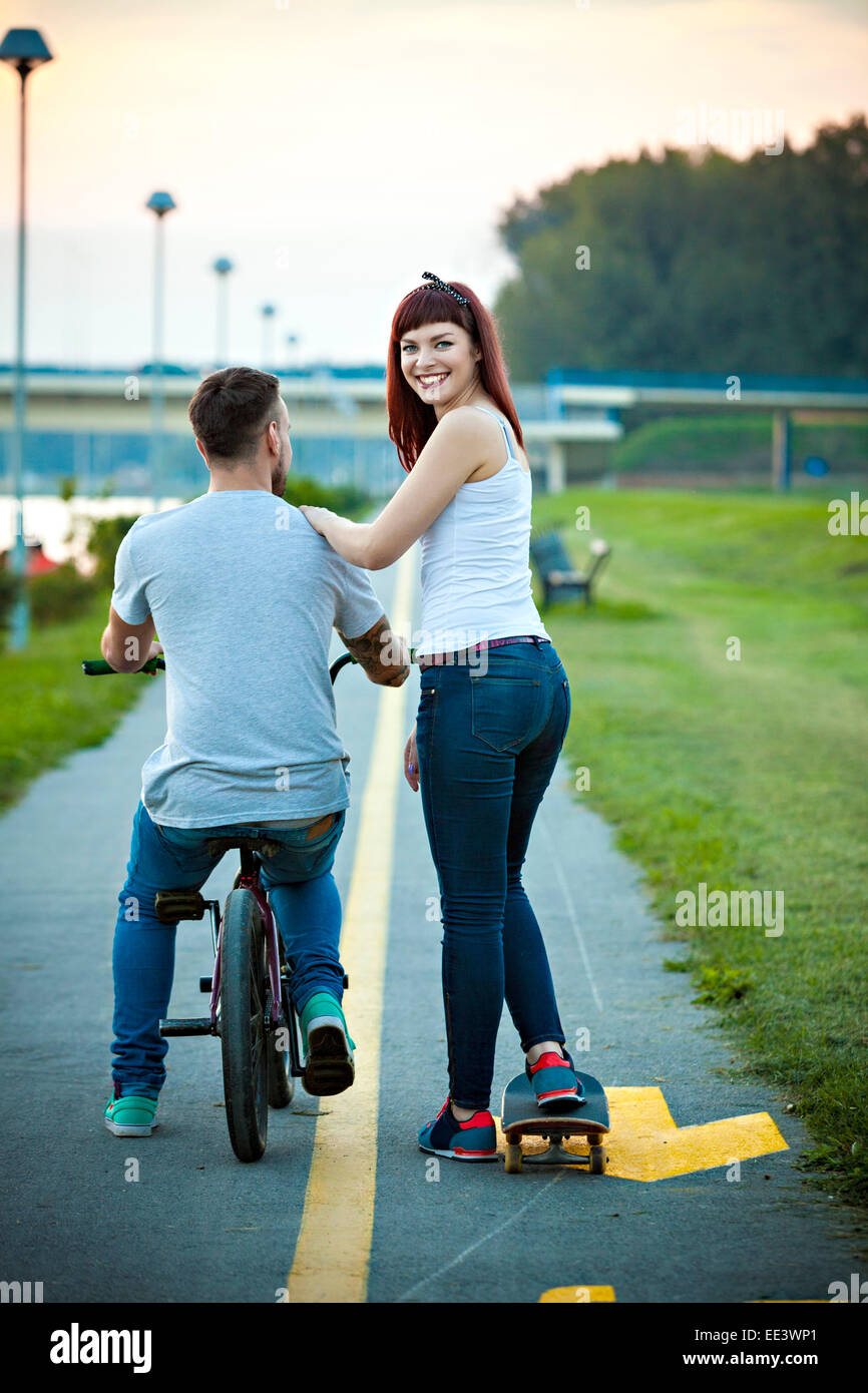 Jeune couple avec vélo BMX et skateboard en plein air Banque D'Images