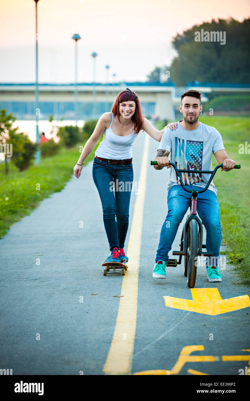 Jeune couple avec vélo BMX et skateboard en plein air Banque D'Images