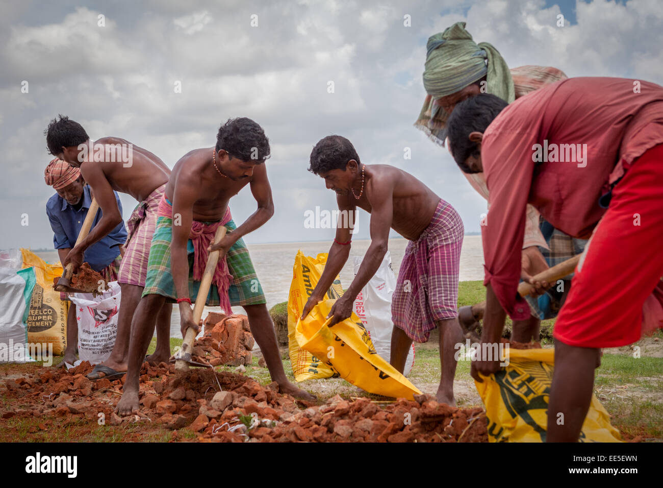 Les travailleurs remplissant des sacs de morceaux de brique pour le projet de contrôle de l'érosion fluviale sur la rive de la rivière Rupnarayan à Tamluk, Bengale-Occidental, Inde. Banque D'Images