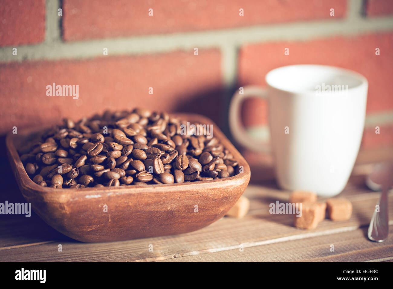 Les grains de café dans un bol avant de brick wall Banque D'Images