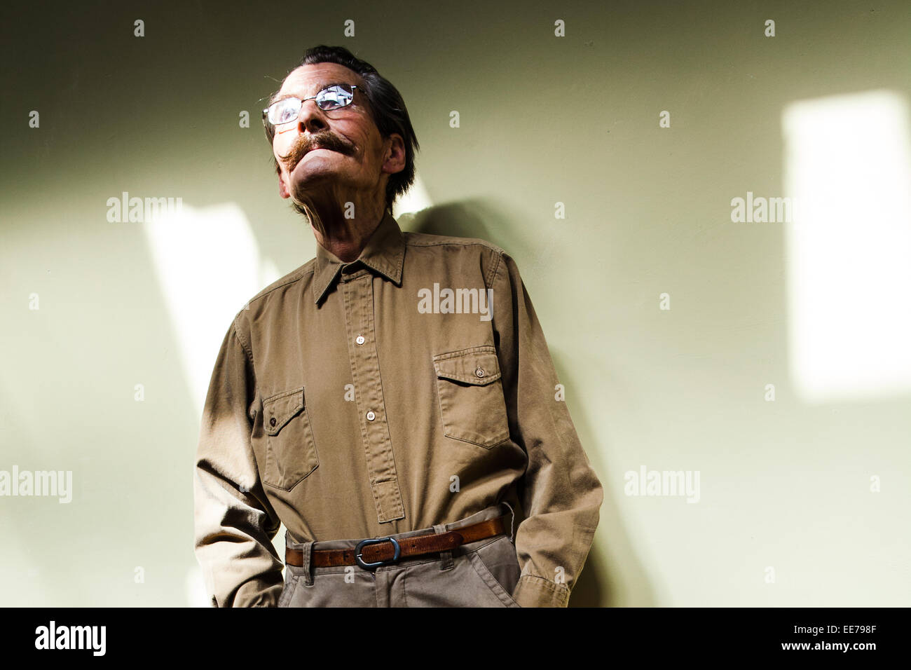 L'homme dans son 60s avec moustache portant chemise et le pantalon kaki. Banque D'Images