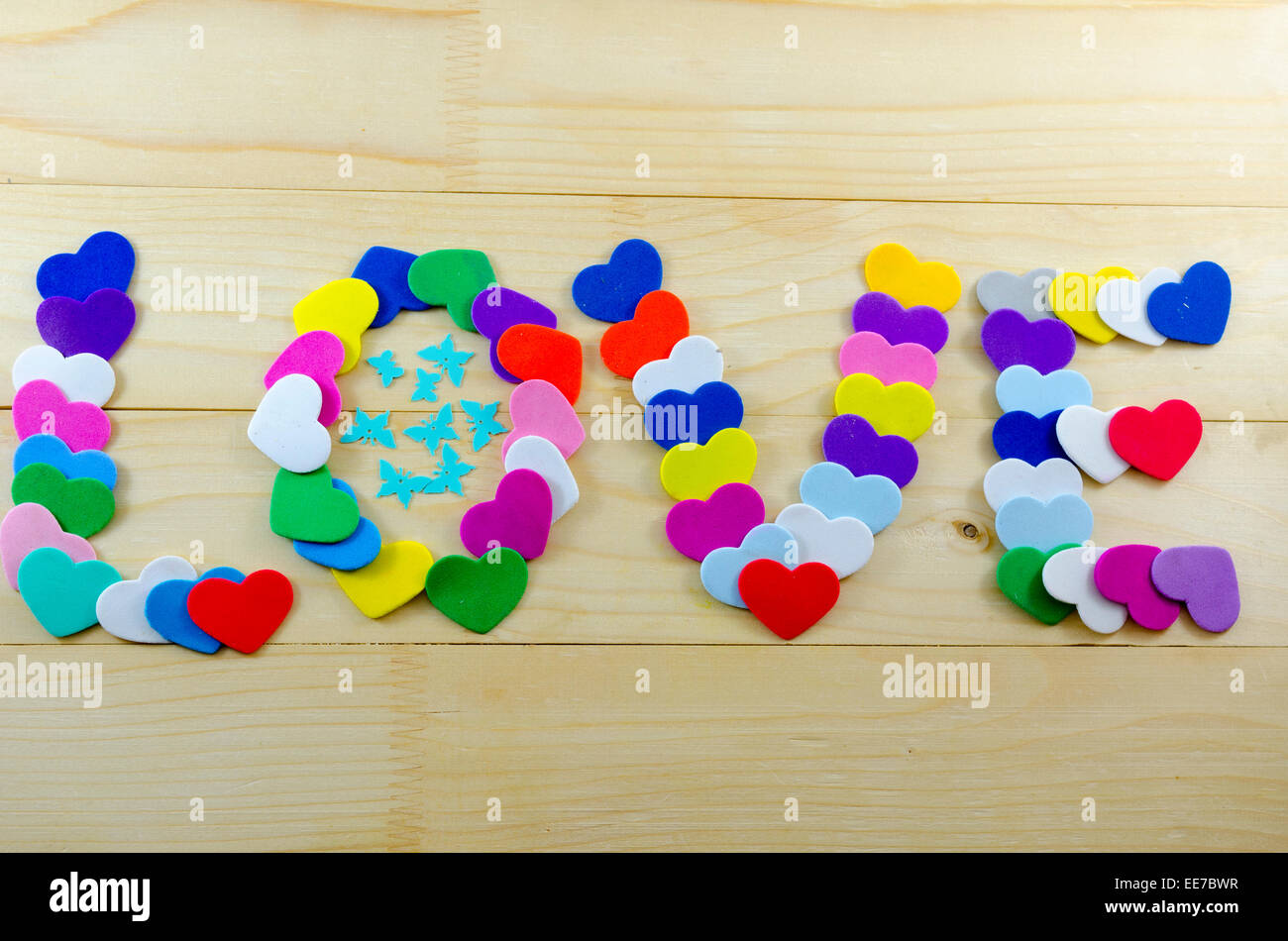Le mot amour écrit avec coeurs en carton décorée de papillons de papier sur une table en bois Banque D'Images