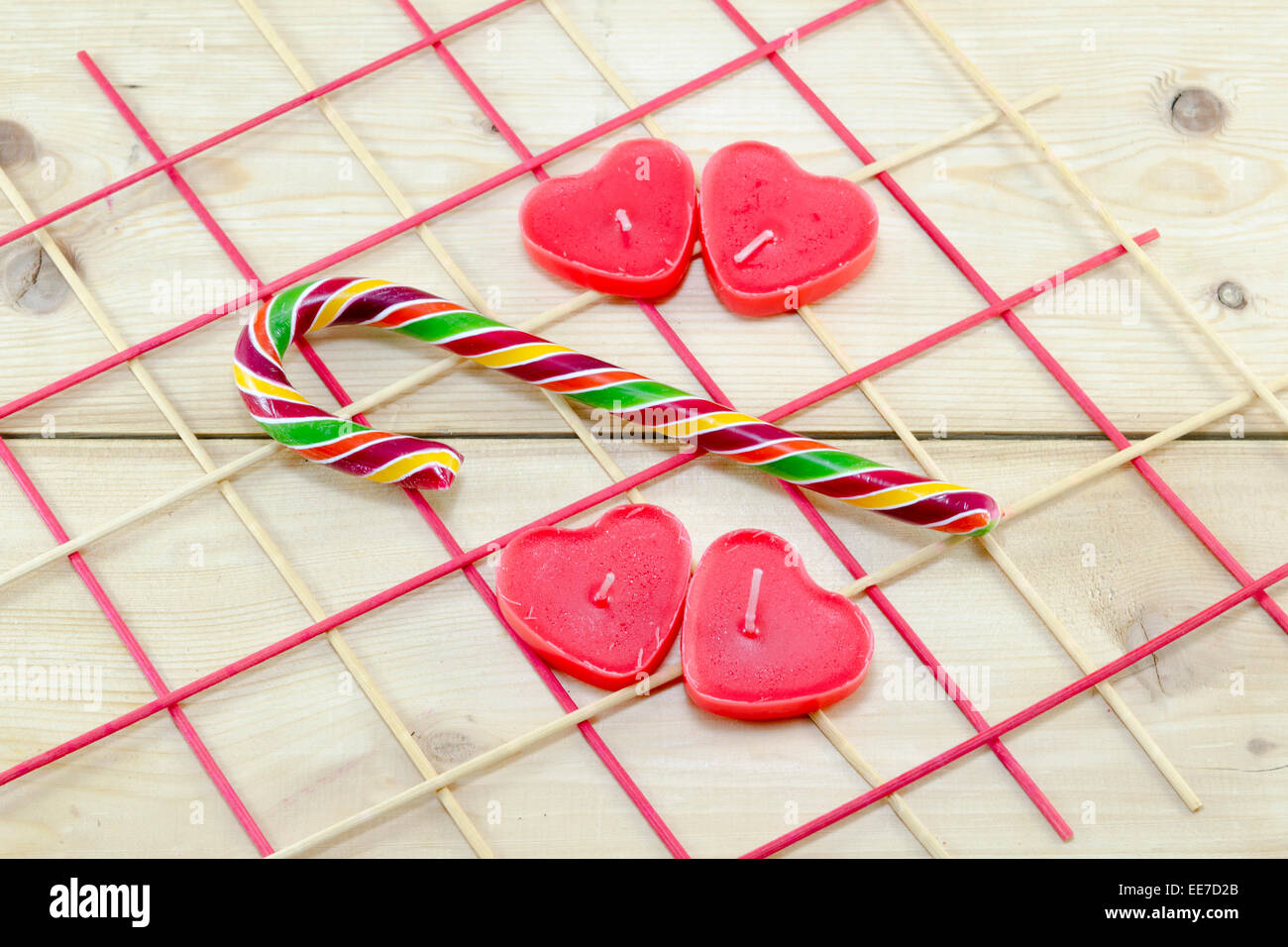 Bougies en forme de coeur rouge et une canne sur un tableau intéressant arrangement Banque D'Images
