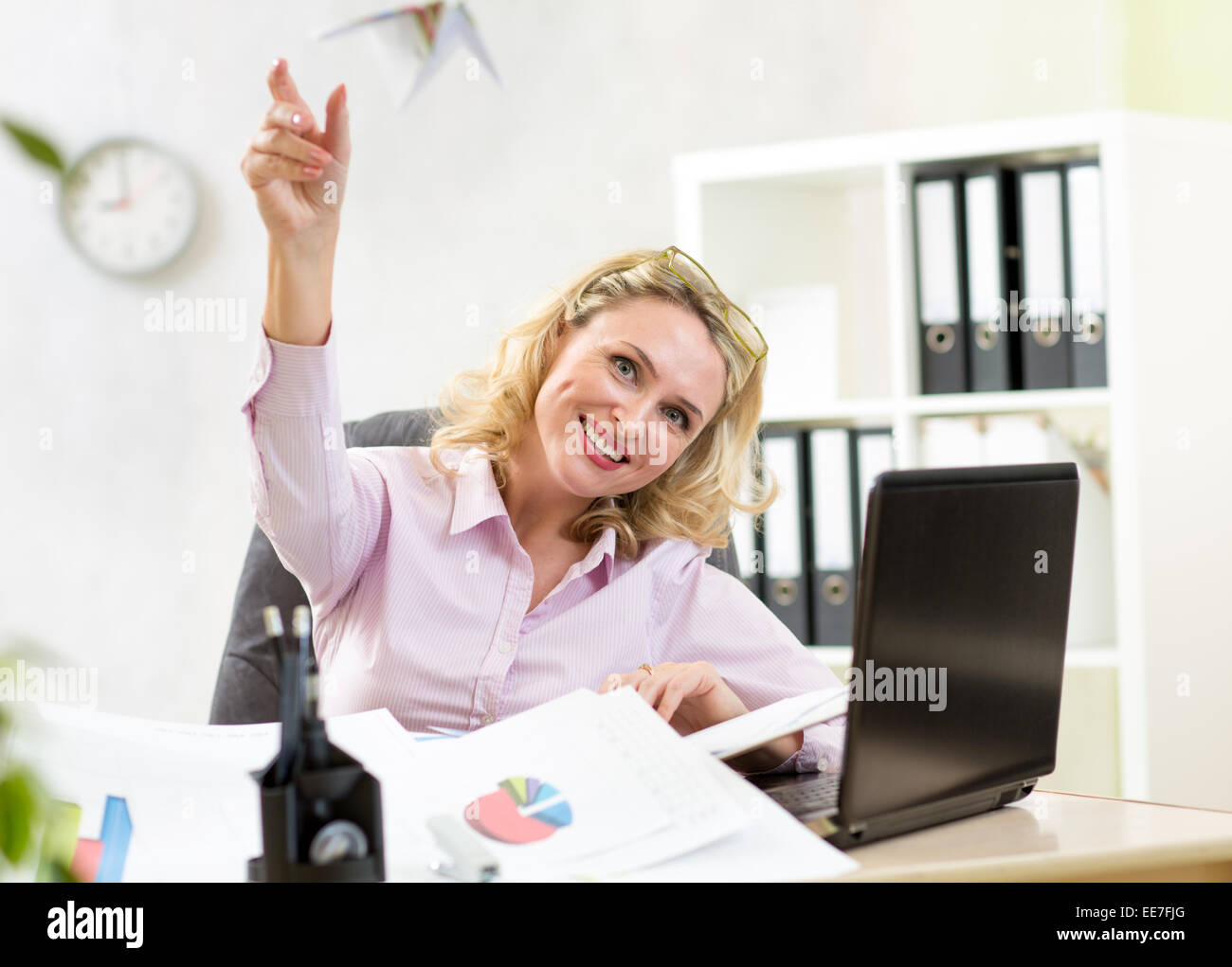 Businesswoman throwing paper airplane in office Banque D'Images