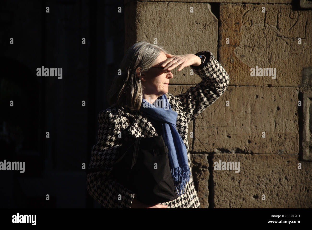 Ombrage femme yeux contre le soleil, à l'extérieur de l'hôpital historique de la Santa Creu, dans El Raval quartier de Barcelone Banque D'Images