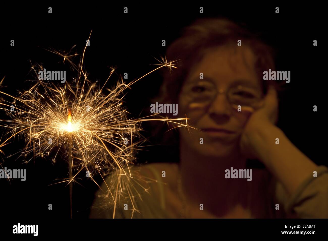 Woman looking at burning sparkler Banque D'Images