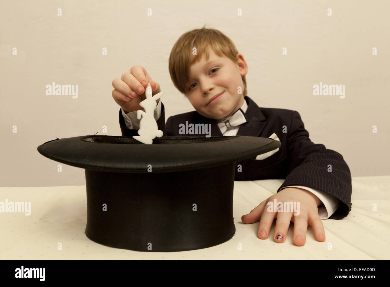 Jeune garçon habillé en magicien tirant un lapin de son chapeau haut de forme Banque D'Images