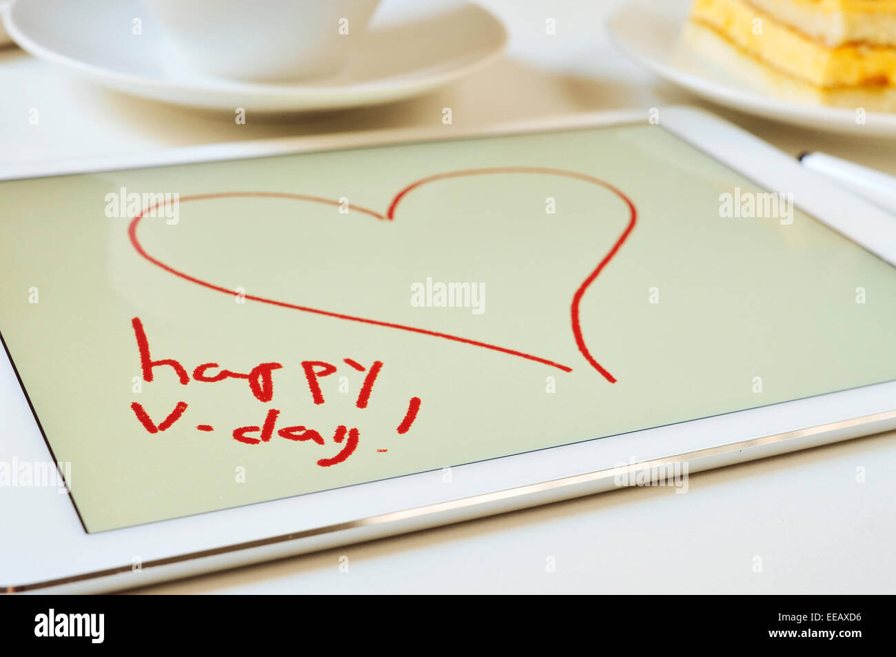Le texte heureux v-day et un coeur dessiné dans un éditeur graphique d'une tablette sur un set de table pour le petit déjeuner Banque D'Images