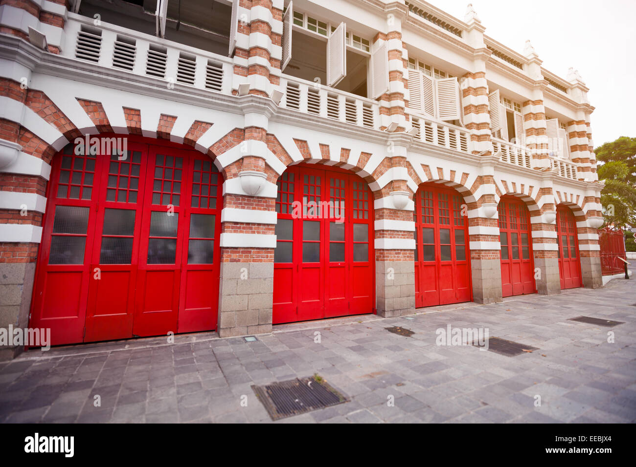 Façade en briques rehaussée, attrayant et peint en rouge vif les portes de garage d'une caserne à Singapour. Banque D'Images