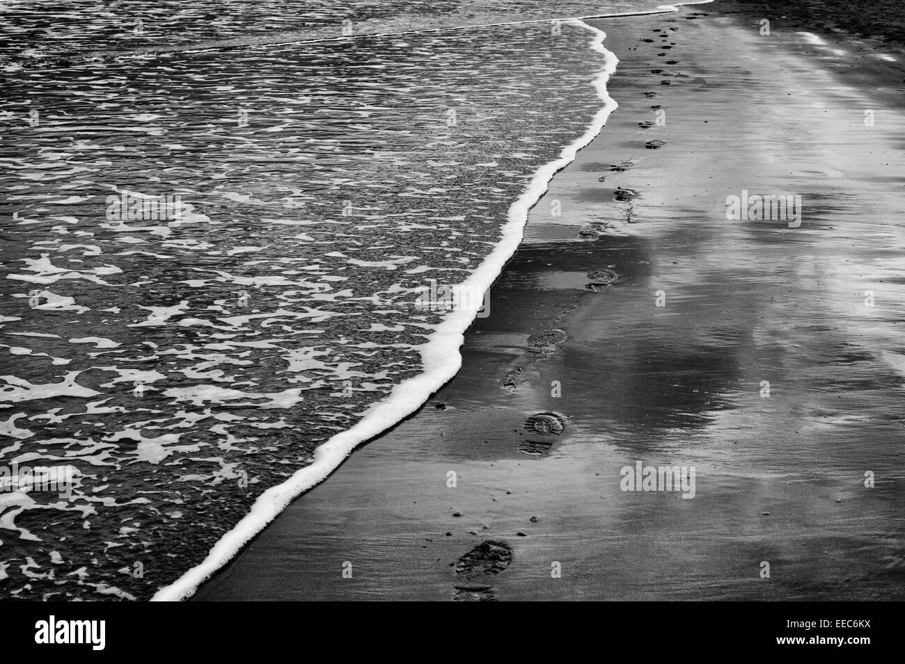 Des traces de pas dans le sable à côté de la mer à marée basse. UK. Le noir et blanc Banque D'Images