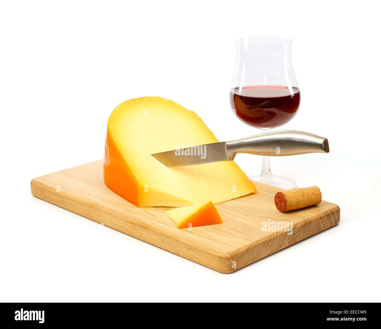 La vie encore d'un couteau à fromage jaune sur une planche à découper avec un verre de vin rouge contre fond blanc Banque D'Images