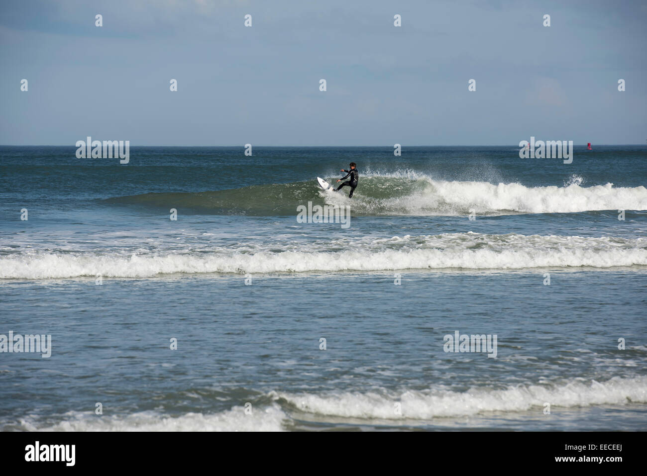 Jeune homme en noir combinaison réduit sur une vague qu'il surfe une vague sur la côte est de la Floride près de Daytona Beach. Banque D'Images