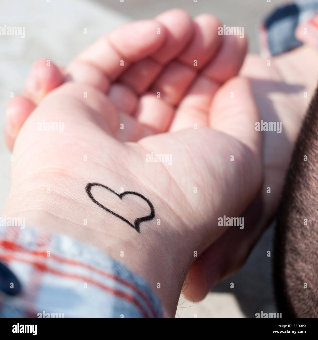 Libre du poignet d'un jeune homme avec un coeur tatoué dans c Banque D'Images