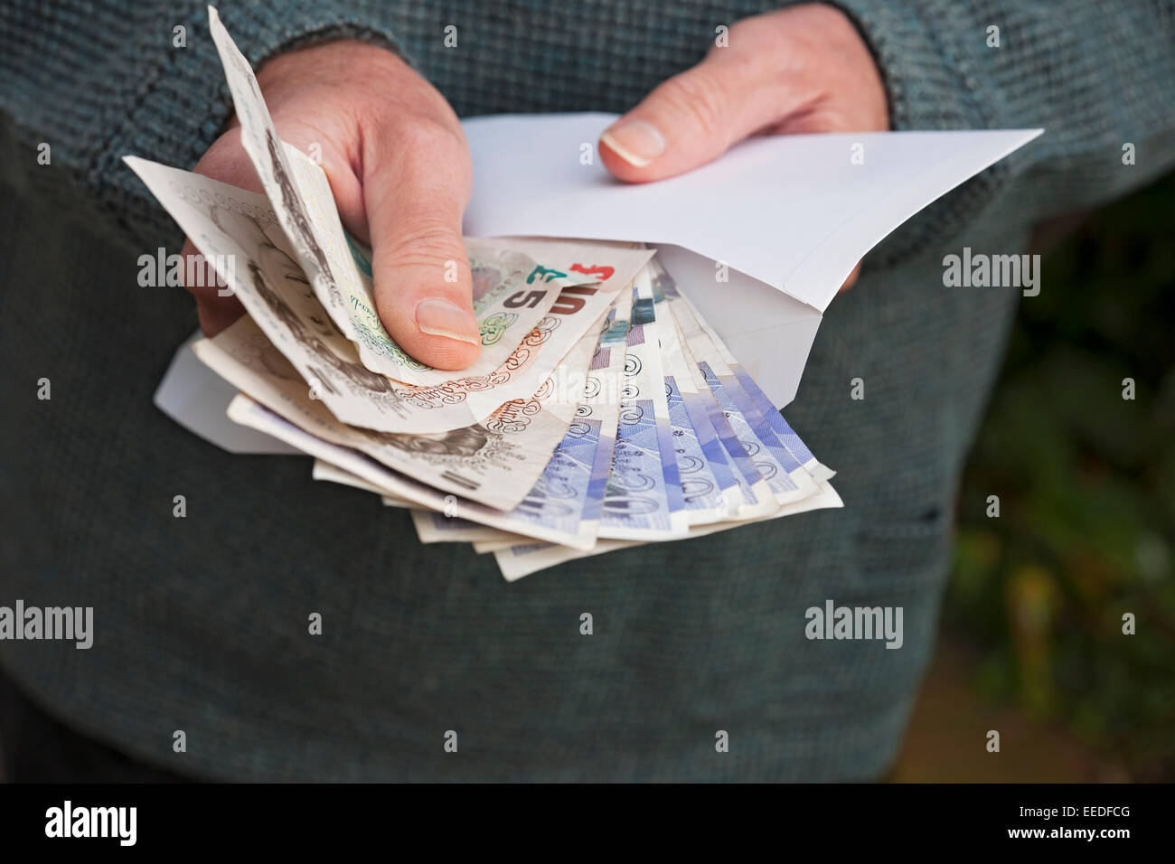 Gros plan de l'homme personne tenant l'argent anglais billets de banque billets de banque espèces et enveloppe blanche fraude Angleterre Royaume-Uni Grande-Bretagne Banque D'Images