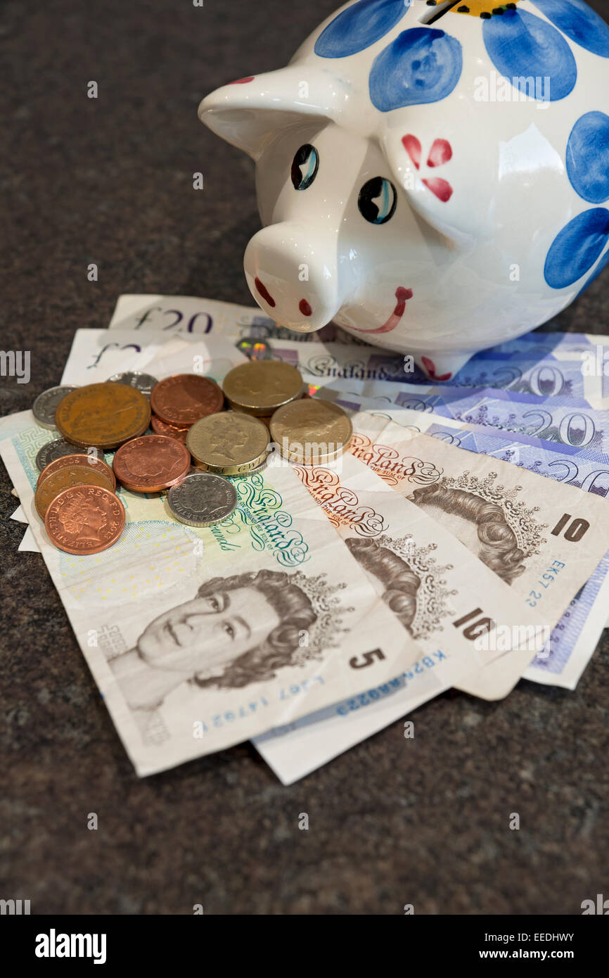 Gros plan de Piggy Bank et billets de banque anglais billets de banque et pièces de monnaie finance concept d'affaires Angleterre Royaume-Uni GB Grande-Bretagne Banque D'Images
