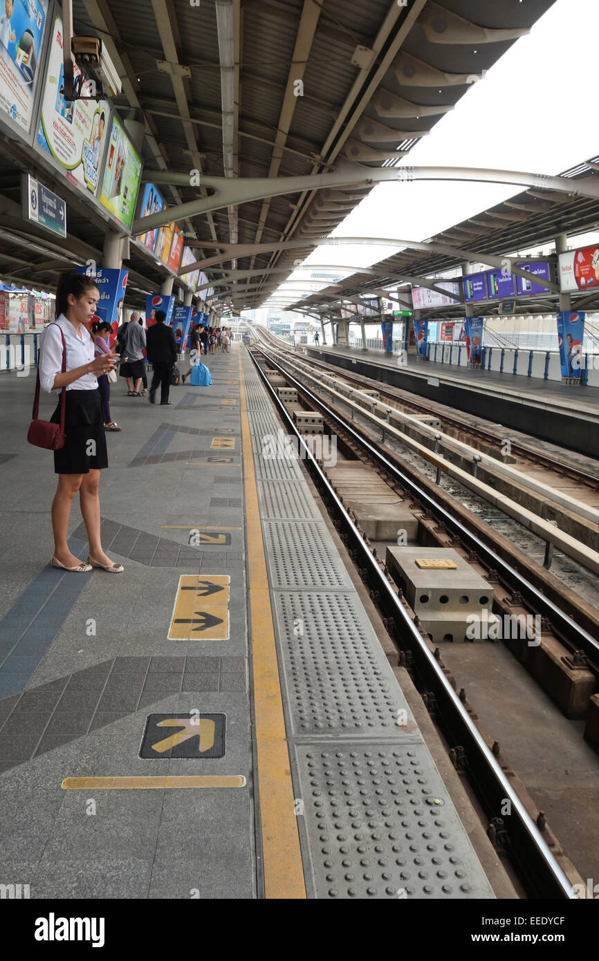 Jeune femme asiatique en attente à la station de Sathorn, les transports publics urbains train skytrain, Bangkok, Thaïlande, Asie du sud-est. Banque D'Images