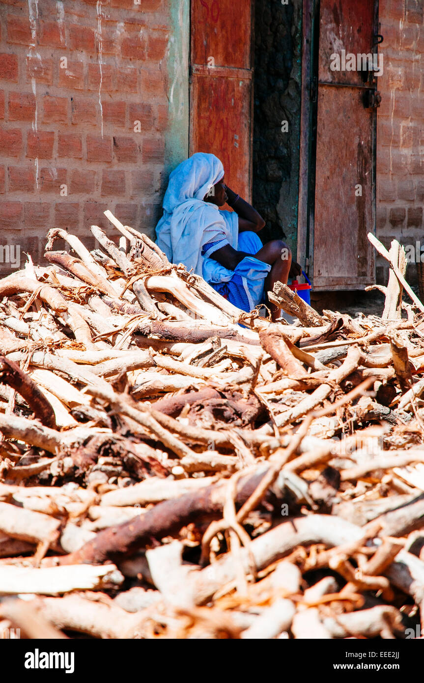 Femme assise à côté de bois dans les rues de Djenné, au Mali. Banque D'Images