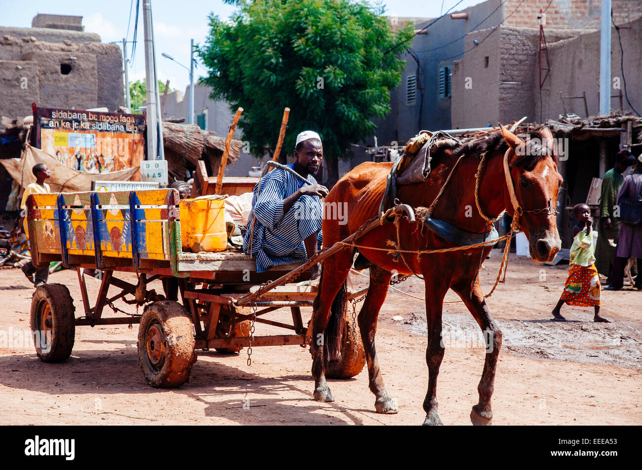 Homme voyageant sur un chariot à cheval dans les rues de Djenné, au Mali. Banque D'Images
