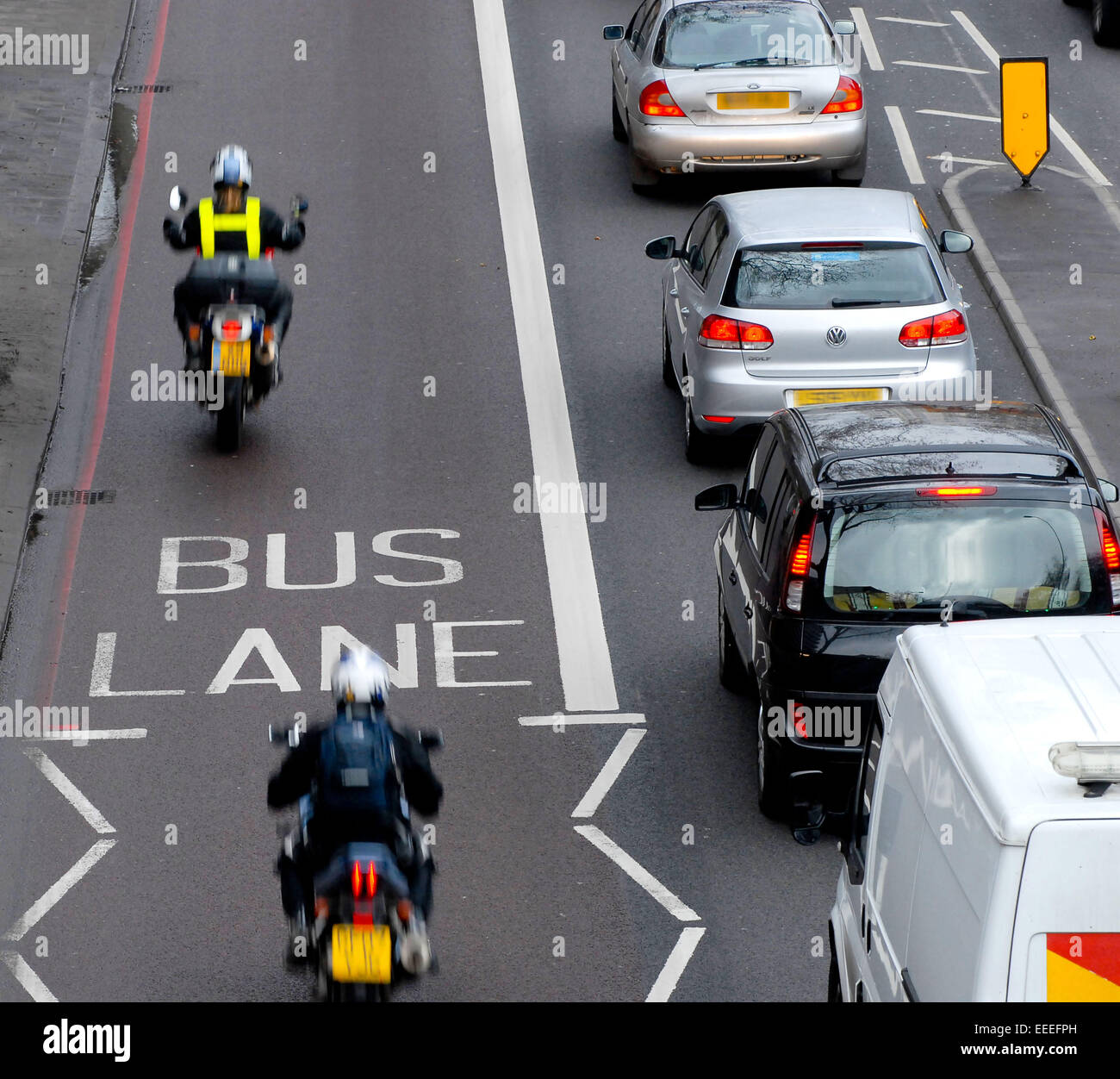 Voitures à l'arrêt alors que les motos de route passer sur le bus lane Banque D'Images